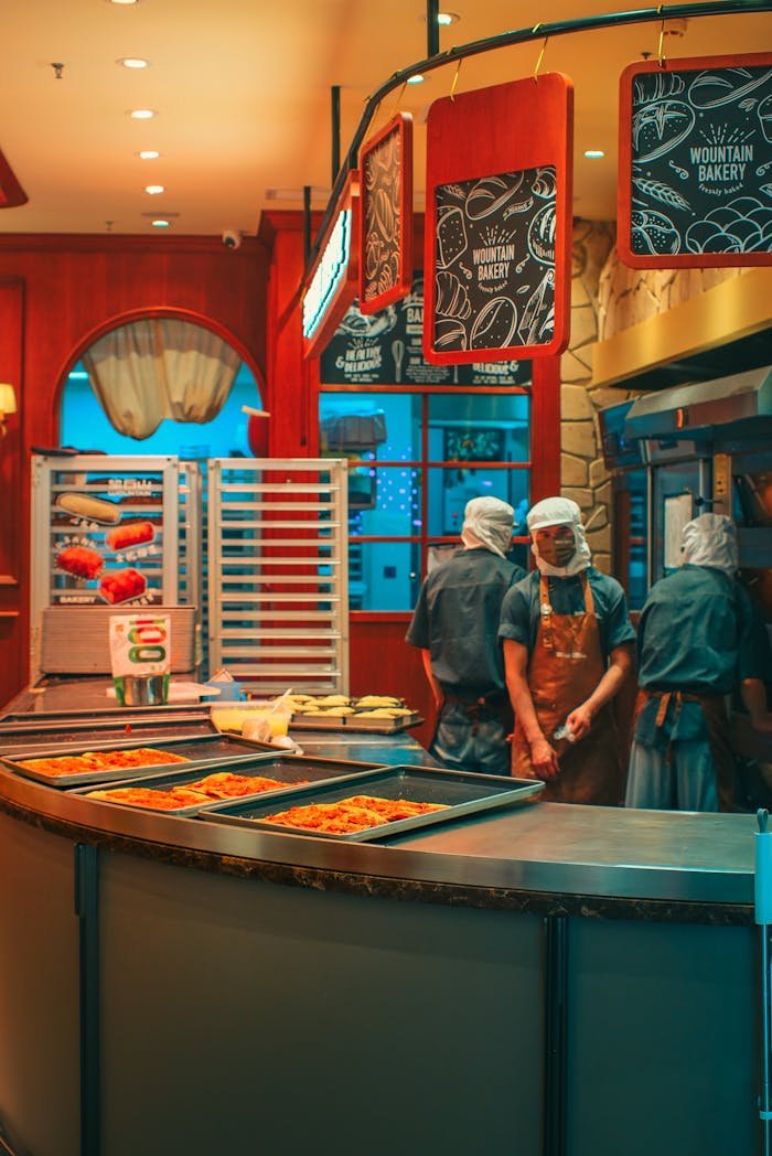 Industrial bakery scene with chefs preparing food, warm interior lighting adds ambiance.