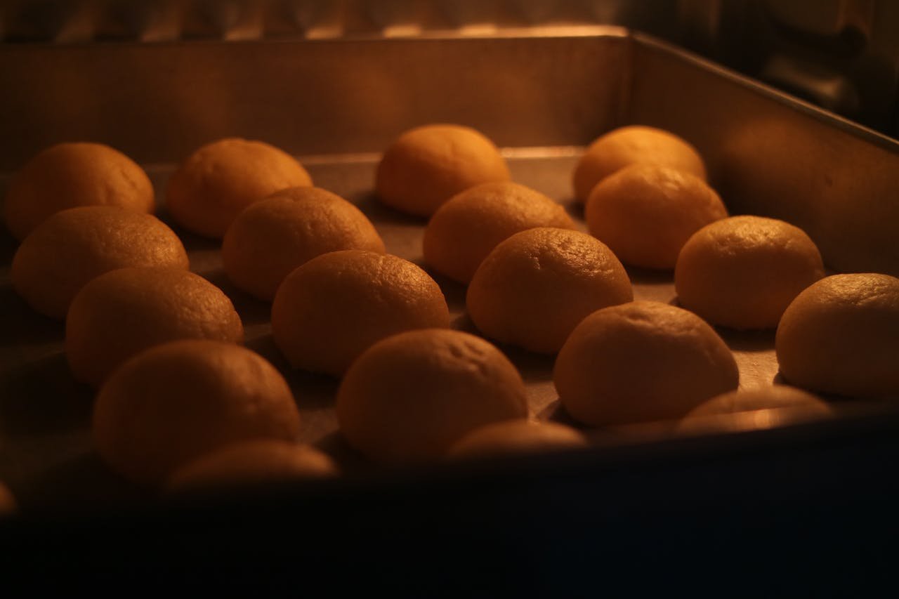 Golden buns baking in a warm oven setting, showcasing the art of bread-making.